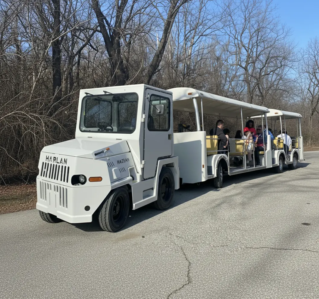 A white Harlan tractor pulls a filled passenger tram up a hill