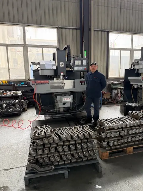 CNC milling machine operator standing next to a vertical machining center with stacks of precision-machined metal hardware components.