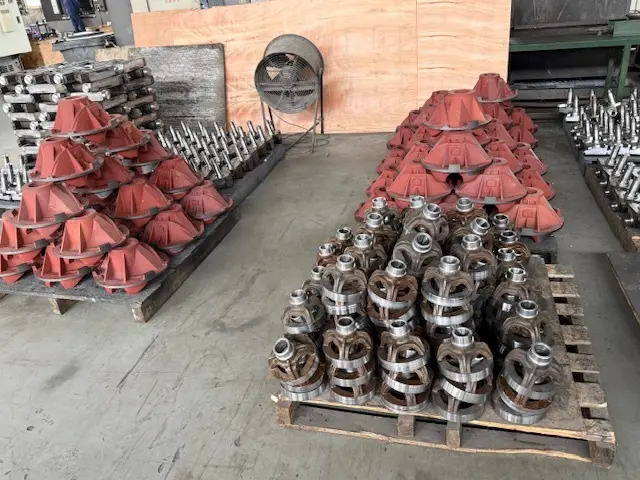Pallets of precision-machined cast iron housings and industrial metal hardware components inside a manufacturing facility.