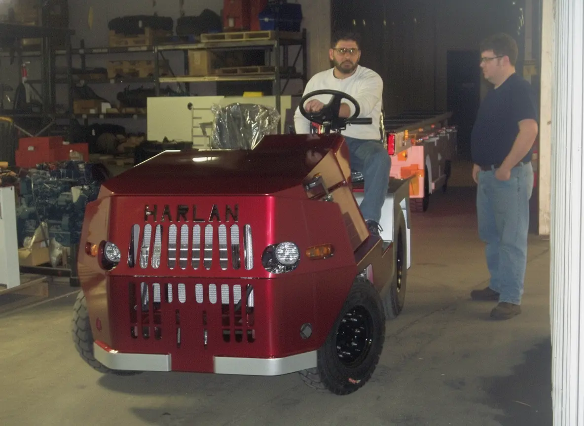A dark red Harlan tractor given a safety check before shipment